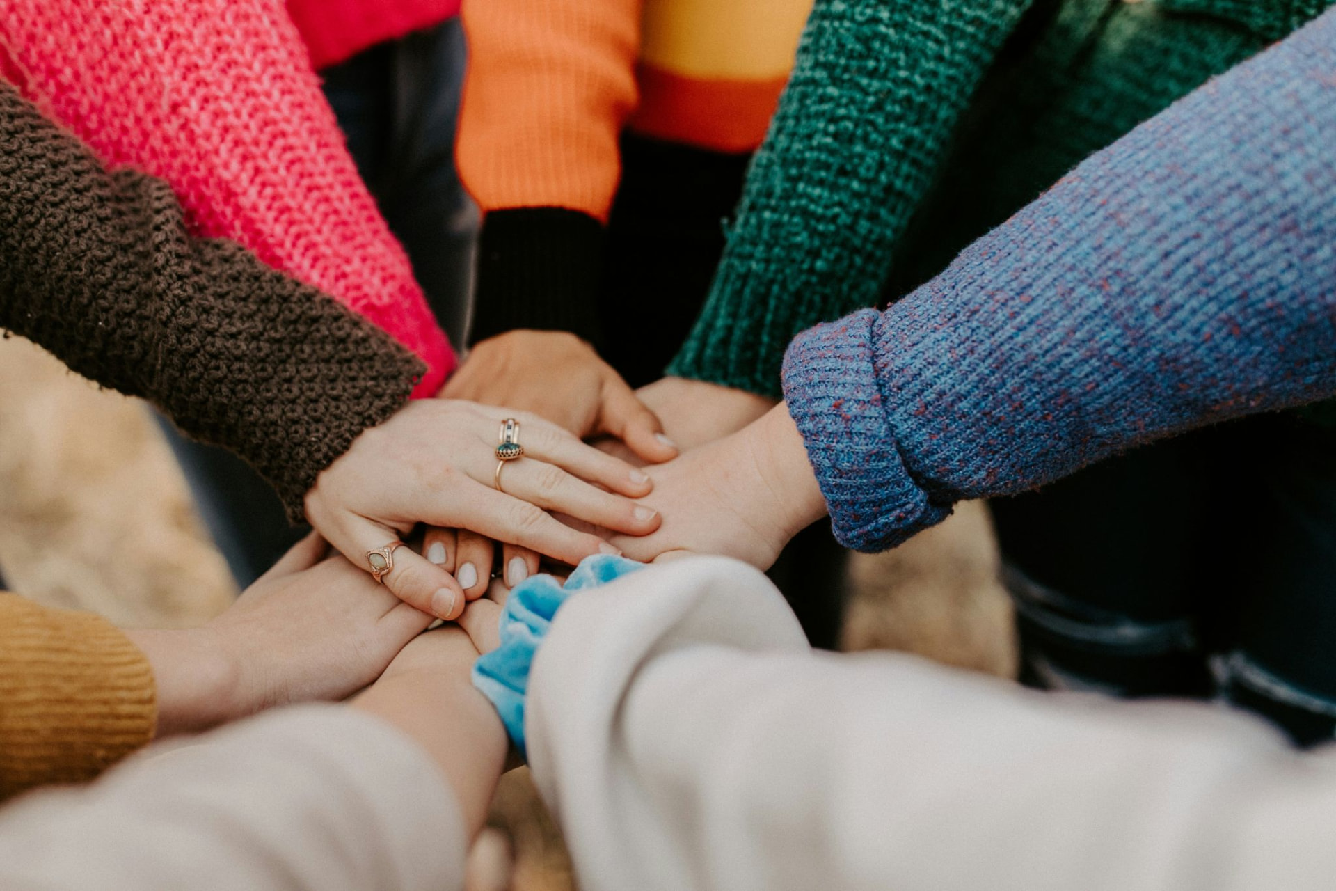 A group of people placing their hands together in a gesture of support